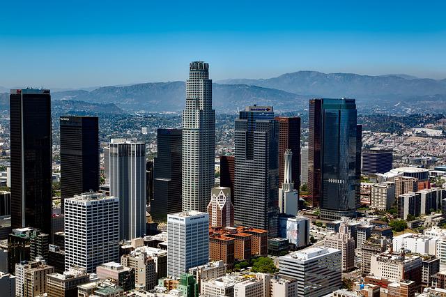 A half aerial view of Los Angeles' skyline. Mountains can be seen in the background.